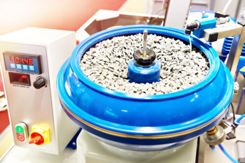 Finishing powdered metal components with vibratory tumbling